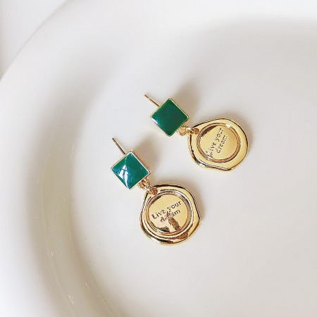 Wholesale Gold Plated Green Enamel Pendant Dangle Earrings (5 Pairs) - A pair of gold-plated dangle earrings with green enamel stones and a circular charm engraved with 'Live your dream'.