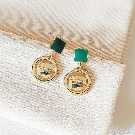 Full set view of the gold-plated earrings with green stones and 'Live your dream' pendants.
