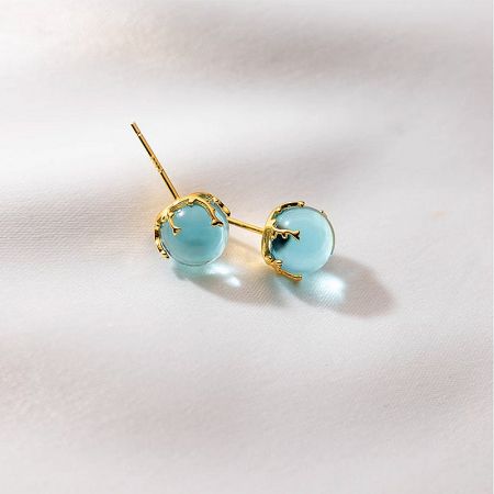 Detailed view of the gold-plated sterling silver earrings with light blue gemstones.