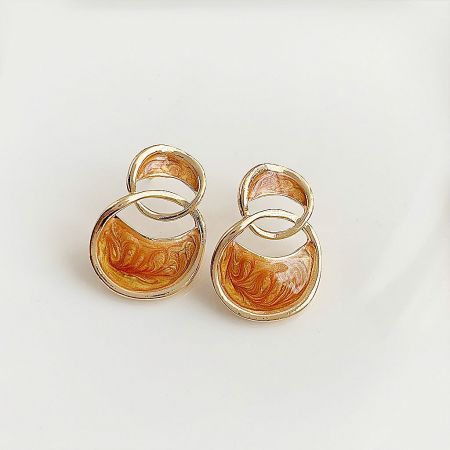 Another angle of the gold stud earrings, displaying the vibrant marbled orange and yellow design.
