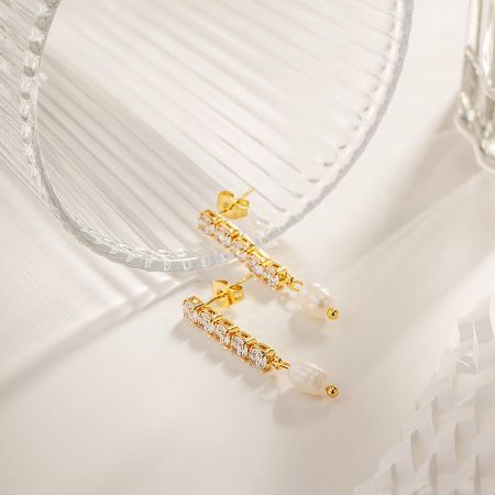 A clear product view of the pair of pearl and zircon tassel earrings against a neutral backdrop.