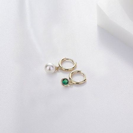 Side view of the pearl and emerald huggie hoop earrings showcasing the gold plating.