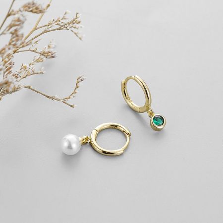 Another angle of the gold-plated huggie hoops with pearl and green CZ.