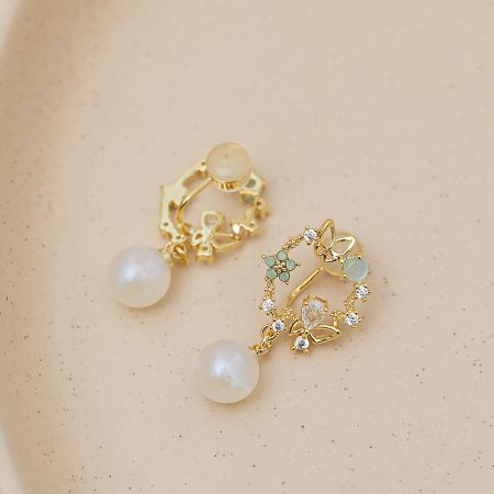A detailed view of the gold earrings highlighting the intricate floral pattern and lustrous white pearls.