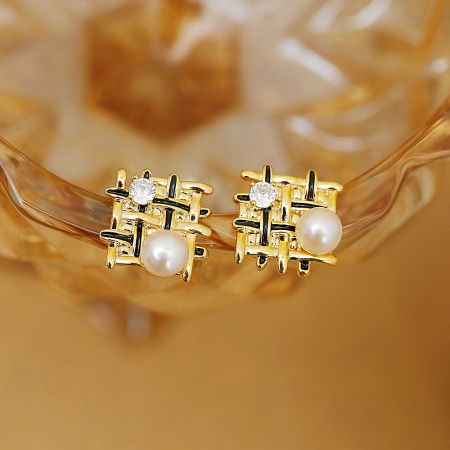 Detailed view of the braided mesh stud earrings with black enamel accents and a central pearl.