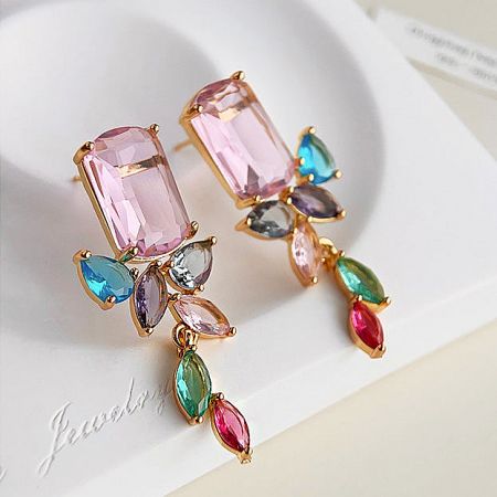 Detailed shot of gold earrings featuring pink and multicolored gemstones.