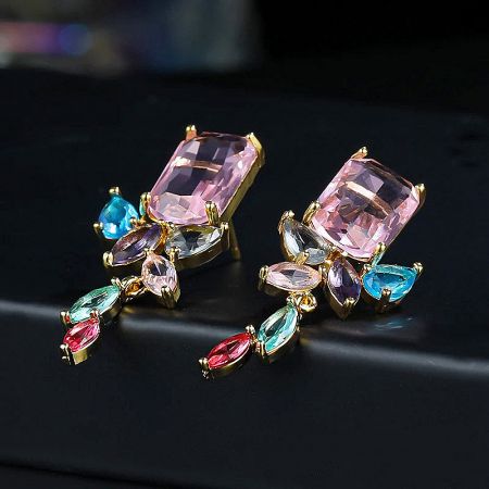 High-end fashion earrings with a large pink stone and colorful dangling gems.