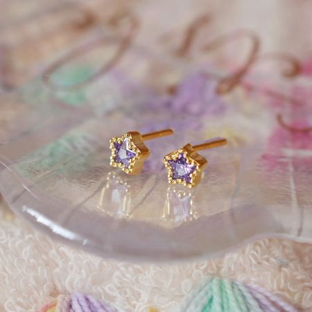 Detailed view of the gold earrings with square-set purple gemstones.