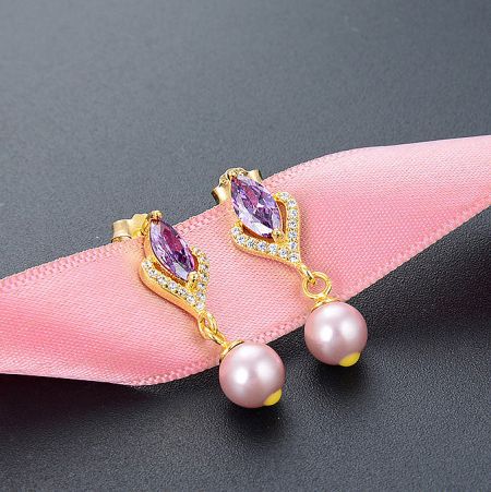 Detailed view of the sterling silver pearl drop earrings with purple crystal zircon.