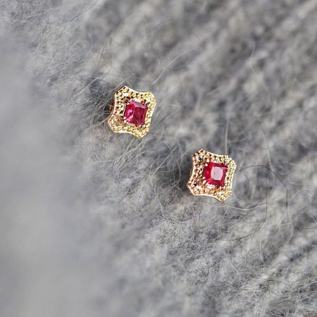 Close-up view of the ruby red stone stud earrings showcasing the intricate gold setting.