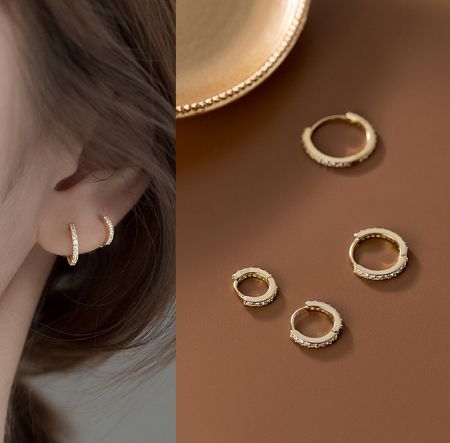 925 Sterling Silver Different Sizes Huggie Earrings - A pair of 925 sterling silver huggie earrings with a polished gold finish and sparkling cubic zirconia stones, showcased against a clean background.