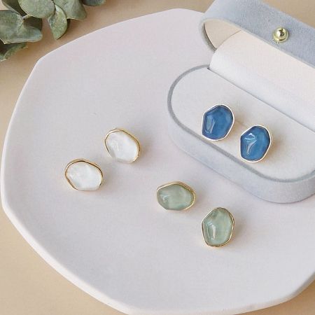 The collection of geometric resin earrings displayed in a jewelry box.