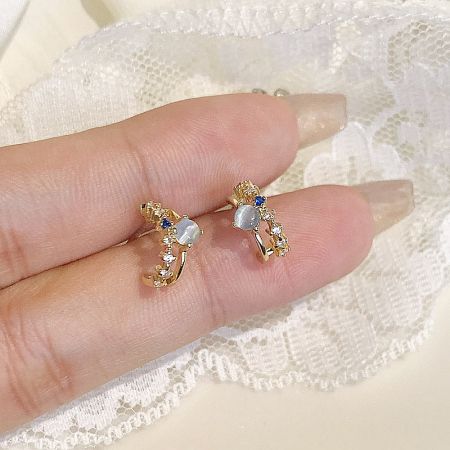 A hand holding a pair of the vintage-style earrings to show scale and detail.