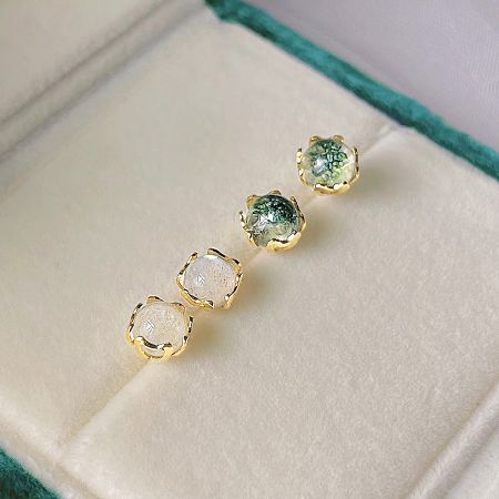 A set of four mini stud earrings with white and green shimmer stones in a gold setting.