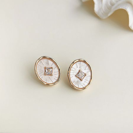 Detailed shot of the elegant gold earrings with white enamel faces and sparkling zircon stones.