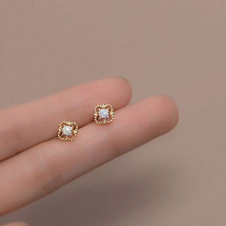 Close-up of square-shaped gold opal stud earrings from the minimalist collection.