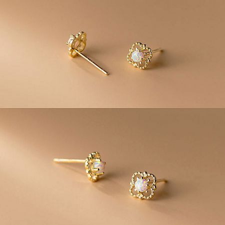 Vintage-style gold stud earrings with a circular filigree pattern and central white gemstone.