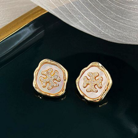 A pair of gold earrings with a delicate white and pink inlay in a flower design.
