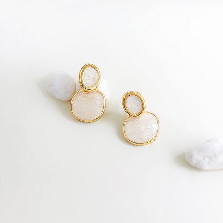 Detailed shot of the double-layered design of the gold and white enamel earrings.