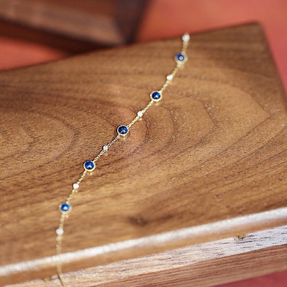 A unique evil eye design bracelet from the set, featuring blue and white beads on a gold chain.