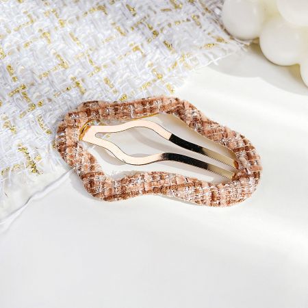 A fashionable gold hair clip with a unique fabric-covered design.