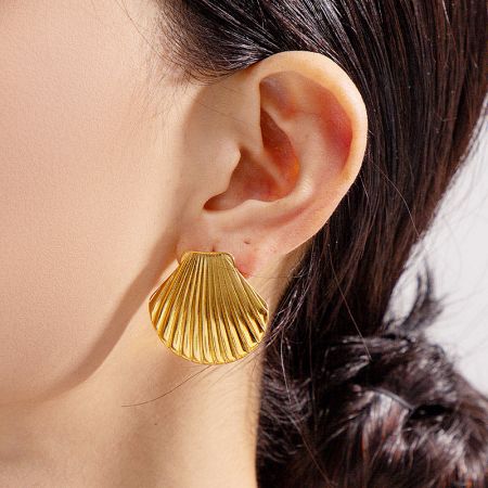 Close-up view of a woman wearing the gold chunky shell stud earring.