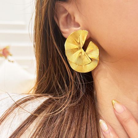 Close-up view of a gold fan-shaped geometric earring.