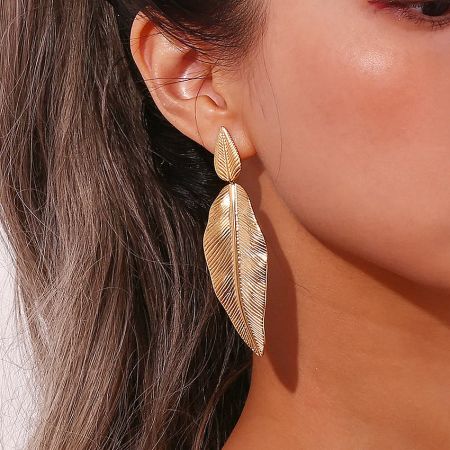 Side profile of a woman wearing the elegant gold feather drop earring.