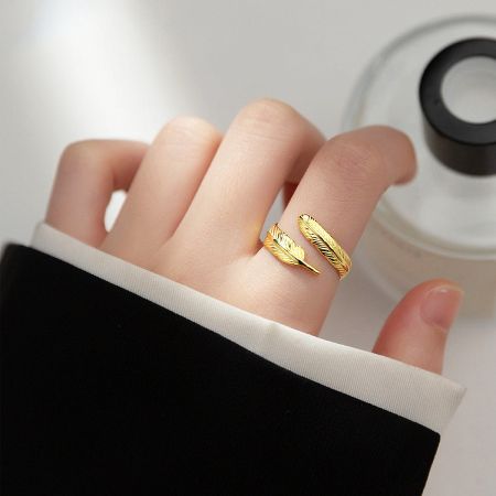 A woman's hand elegantly wearing the gold adjustable feather ring, showcasing its fit and style.