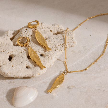 Ocean Beach Style Gold Fish Necklace and Earrings Set - A stunning gold fish-shaped jewelry set, including a necklace and earrings, elegantly displayed on a beige stone with a seashell, perfect for beach-themed styles.