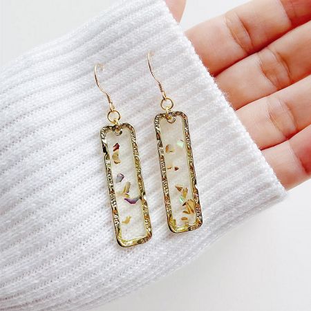 An alternative view of the handmade-style earrings, showing the unique flecked design within the gold setting.