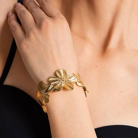 Lifestyle image showing the gold floral bracelet worn by a woman.