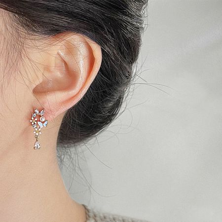 Model wearing the gold floral butterfly earring to demonstrate its size and appearance.