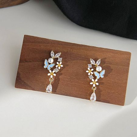 The floral butterfly earrings presented on a natural wood display stand.