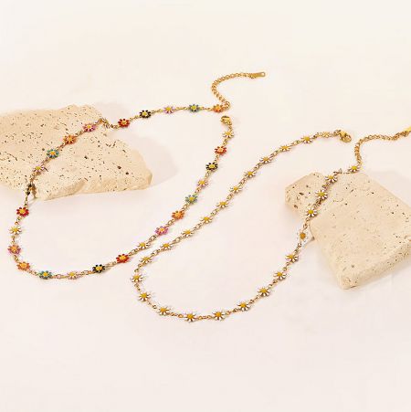 Two gold chain necklaces with floral charms, one with white daisies and one with colorful daisies.