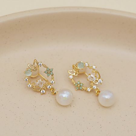 Another angle of the gold floral earrings, showcasing the sparkling clear crystals and small green stones.