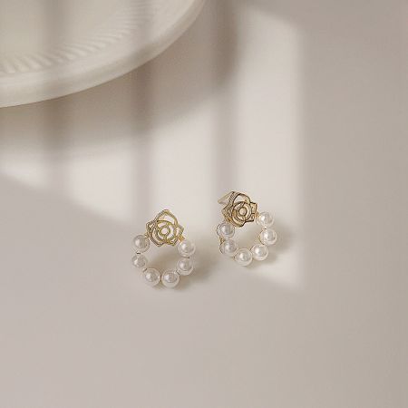 Close-up view of the gold floral pearl earrings highlighting the detailed craftsmanship.