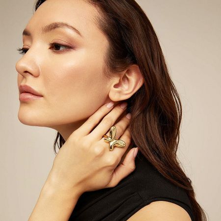 A woman showcasing the elegant floral-inspired gold ring on her finger.