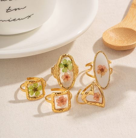 A collection of five gold rings with various floral designs, showcasing the style of JR Fashion Accessories.