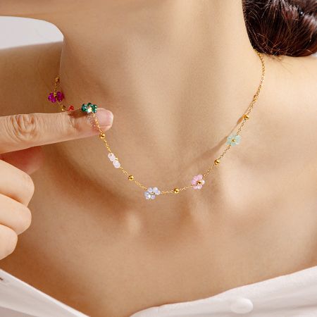 A studio shot of the gold floral charm necklace on a neutral background.