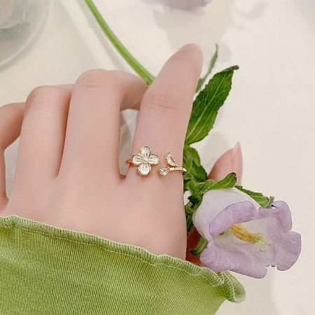 A model's hand wearing a charming gold ring with a flower and bow design from the collection.