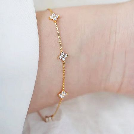 The elegant four-leaf clover bracelet worn on a wrist, highlighting its fit and style.