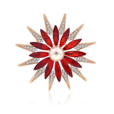 Gold flower brooch with a central pearl, red gemstones, and diamond accents