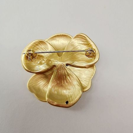 Back view of the gold flower brooch, showing the secure pin clasp for attachment.