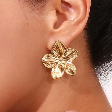 Detailed side view of the gold sakura flower earring worn on an ear.