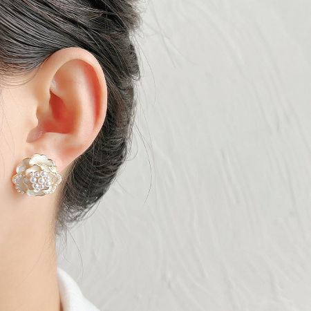 Detailed close-up of the gold-plated camellia earring with pearl center.