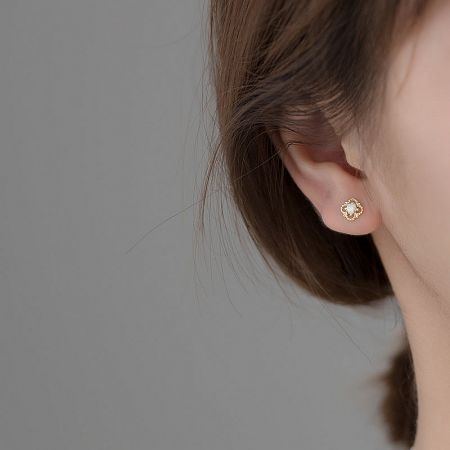Model wearing a flower-shaped gold and opal stud earring to showcase its size and style.