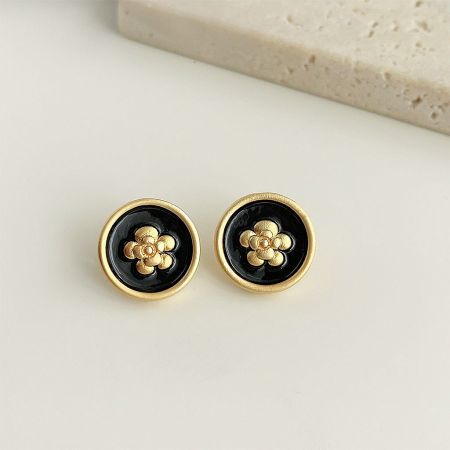 A clear view of the earrings, highlighting the gold rim, black enamel background, and detailed gold floral pattern.