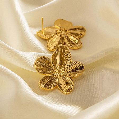 Elegant gold blossom earrings showcased on a luxurious cream satin background.