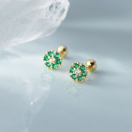 Detailed view of the gold-plated flower stud earrings featuring vibrant green and clear cubic zirconia stones.